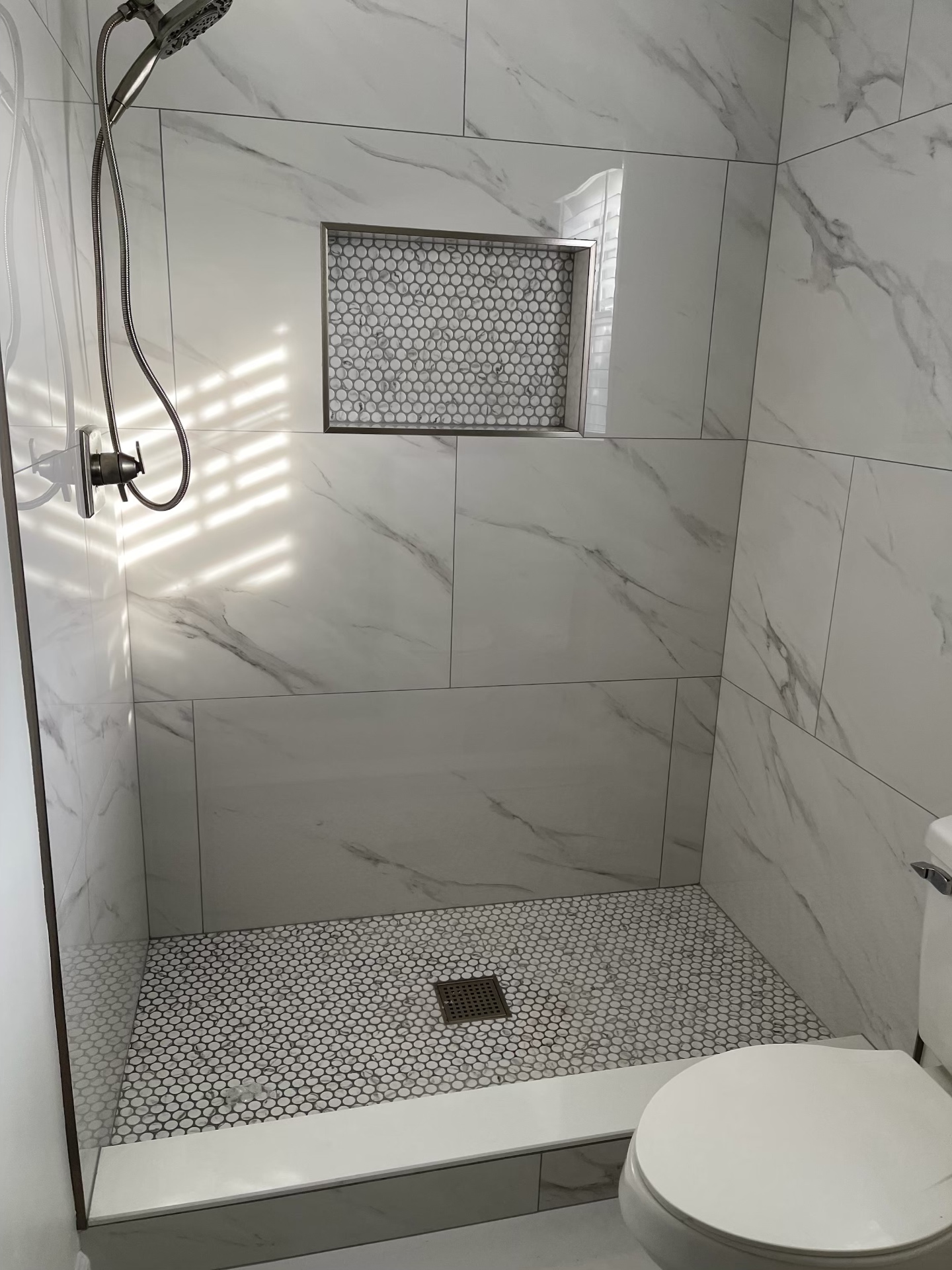 Custom tile shower remodel with marble walls and penny mosaic floor